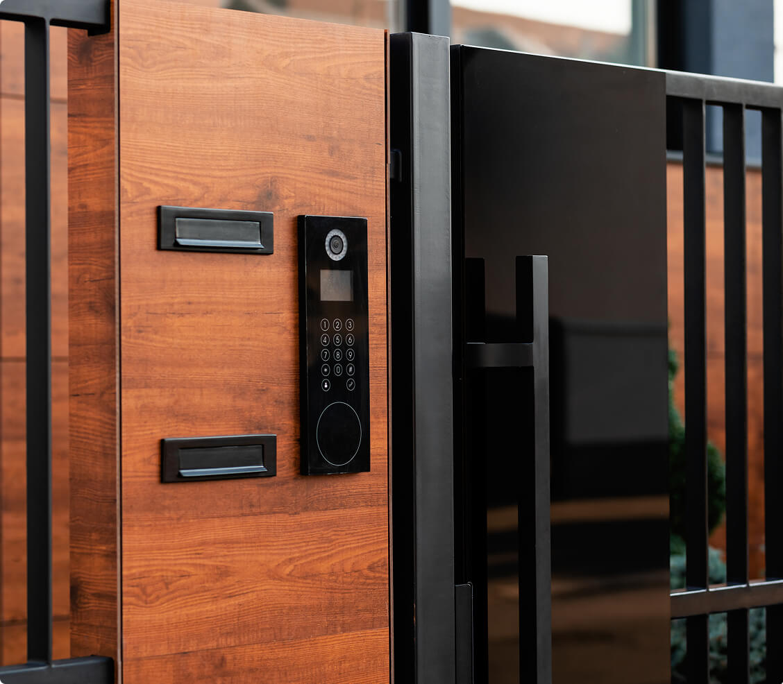 Modern electronic access control keypad with intercom installed on a stylish wooden security gate.