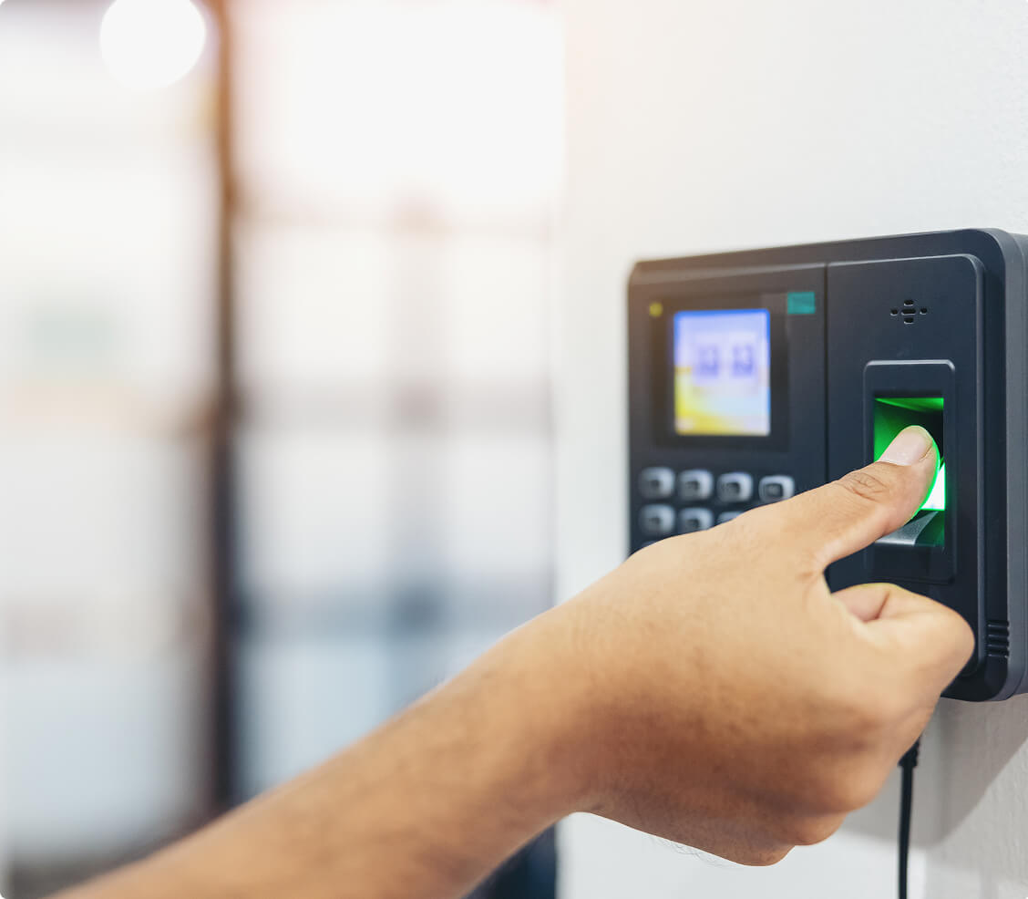 Person using a biometric fingerprint scanner for secure access control system in an office environment.