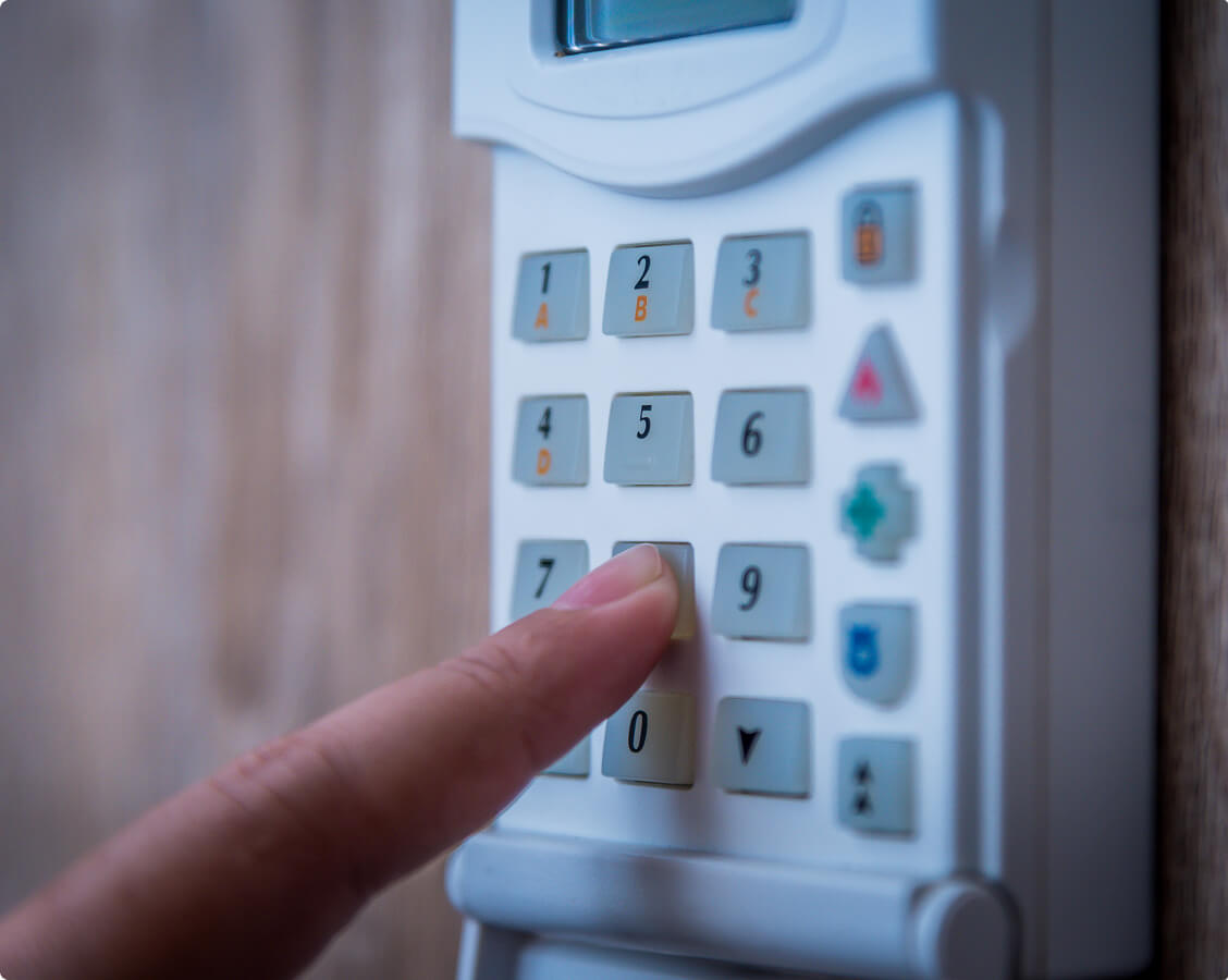 Person entering security code on digital keypad access control system for building entry.