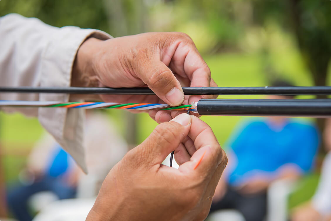 Technician hands installing and connecting fiber optic cables for high-speed internet and telecommunications.