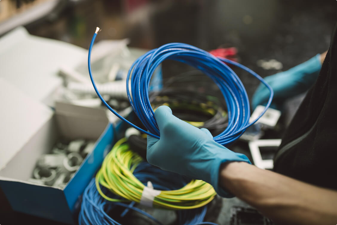 Technician wearing gloves holding blue network cables for structured cabling and security system installation.