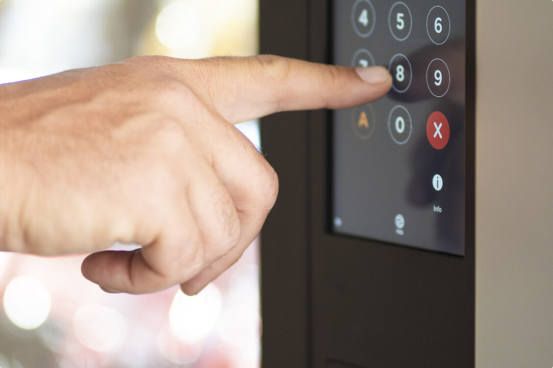 Person entering a security code on a digital keypad access control system for building entry.
